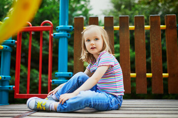 Girl on playground on a sunny day. Preschooler child playing on a slide. Outdoor activities for kids