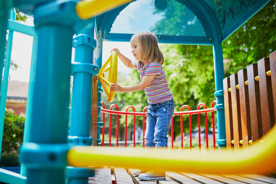 Girl on playground on a sunny day. Preschooler child playing on a slide. Outdoor activities for kids