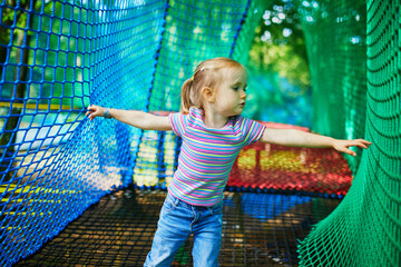 Girl having fun in adventure park. Child on tree top net trampoline. Outdoor activities for small kids