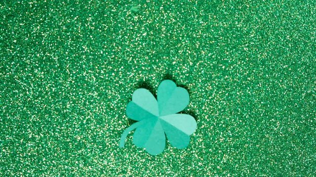St. Patrick's Day. A leaf of clover cut out of paper is spinning on a shiny green background. High quality 4k footage