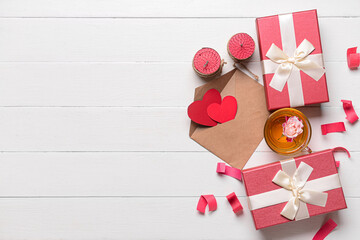 Gifts for Valentine's Day, cup of tea, candles and envelope on light wooden background