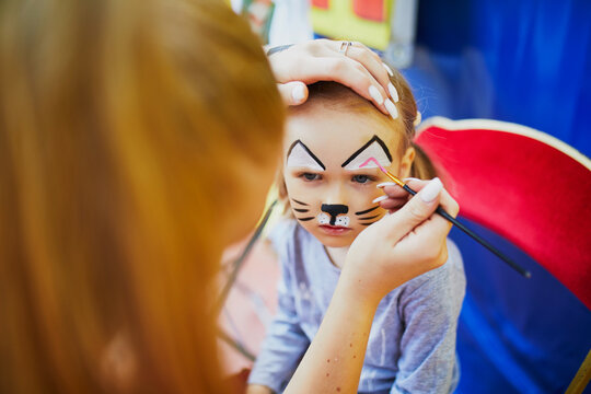 Artist painting little preschooler girl like cat. Creative activities for kids