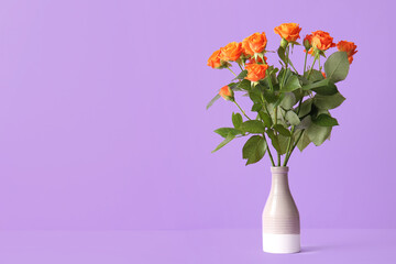 Vase with beautiful orange roses on purple background