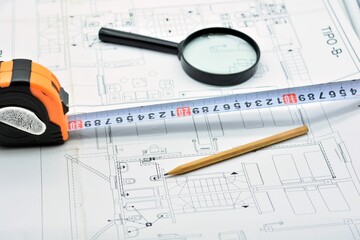 Lápiz, metro y lupa en lo alto de un plano de arquitectura