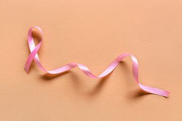 Pink awareness ribbon on beige background. World Cancer Day
