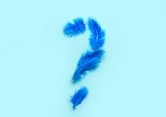 Question mark made of made of feathers on color background