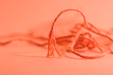 A torn rope with an uneven end. Orange rope on orange background. 
