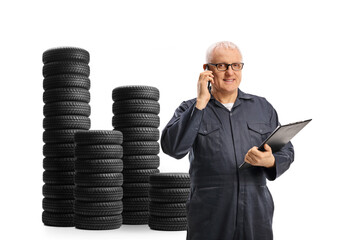 Auto mechanic making a phone call next to a pile of car tires