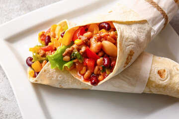 Plate with delicious burritos on table, closeup