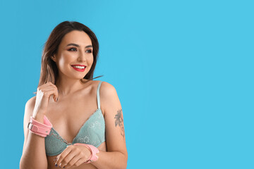 Young woman with handcuffs from sex shop on blue background