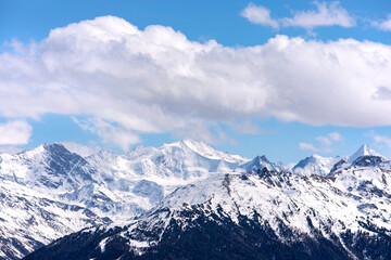 Fototapeta na wymiar Winter alps landscape, top of the snowy mountains with cloudscape, blue sky. Snowy mountain peaks in Swiss alps, Wallis.