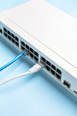 Modern commutator with internet cables on blue background, closeup
