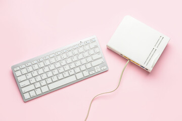 Wi-fi router with internet cable and computer keyboard on pink background