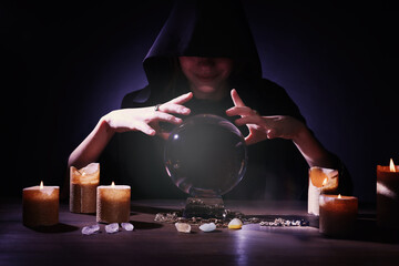 Soothsayer using crystal ball to predict future at table in darkness. Fortune telling