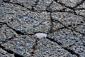 A very small amount of water freezing on the blacktop.  The freezing of water creates cracks during...