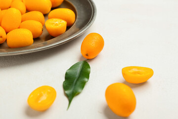 Plate with tasty kumquat fruits on light background