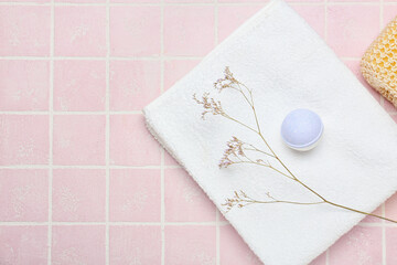 Bath bomb, clean towel and dried flower on color tile