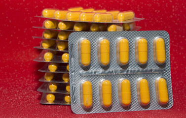 yellow capsules tablets in a silver blister on a red background