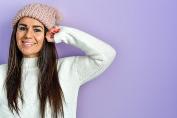 Portrait of Beautiful Smiling   brunette Woman in white  Knitted Sweater and  rose Hat on purple background isolated .Winter Warming Up Concept