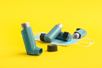 Asthma inhalers and mask on yellow background