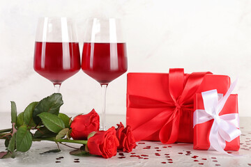 Gifts for Valentine's Day, rose flowers and glasses of wine on light background
