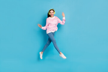 Fototapeta na wymiar Full length photo of youth girl have fun jumper energetic melody headphones isolated over blue color background