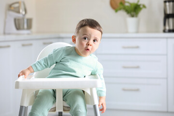 Cute little baby sitting in high chair at kitchen. Space for text - Powered by Adobe