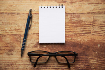 notatnik , długopis i okulary na drewnianym stole © Marcin Łazarczyk