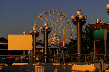 Amusement park at sunset . Ferris wheel in the city . Beautiful street lights