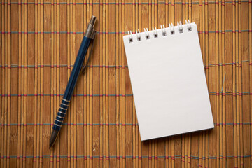 notatnik i długopis na bambusowej podkładce  - obrazy, fototapety, plakaty