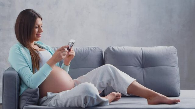 Young pregnant woman is resting at home and expecting a baby. The concept of pregnancy, motherhood, health and lifestyle.