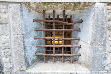 Ancient stone prison wall with metal window bars