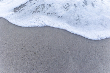 Foaming wave over a beach by the sea