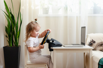 Little girl playing with a computer steering wheel. Little girl playing video game - car racing. Future driver. Getting ready for professional driving. Child driving a car.
