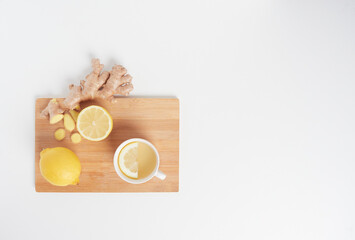 Flat lay view of healthy drink lemon ginger tea in white cup on a wodden board, isolated on white background with copy space.