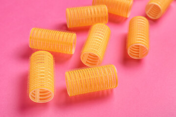 Set of hair curlers on pink background, closeup