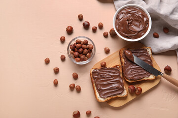 Wooden board of bread with chocolate paste and hazelnuts on beige background