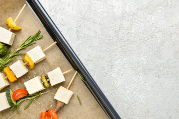 Baking tray with grilled tofu cheese skewers on light background