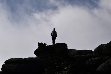 Silhouette of a person on a rock in blue sky