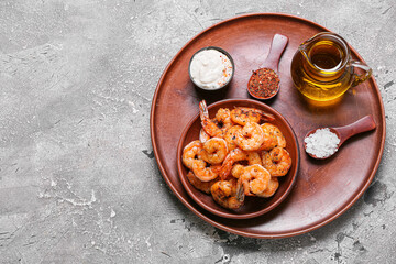 Plate of tasty shrimp tails with sauce, oil and spices on grey background