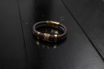 Brown leather male bracelet on the dark wooden desk