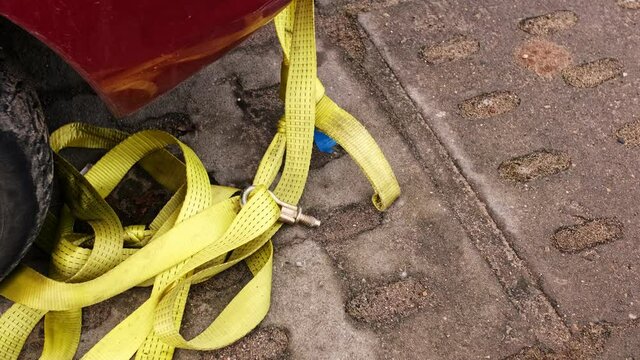 Vehicle Yellow Tow Strap Tape Line with Screw Hitch Towing Hook Attached to Front of Broken Car