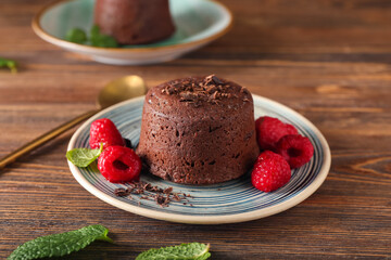 Plate with tasty lava cake fondant and raspberry on wooden background, closeup