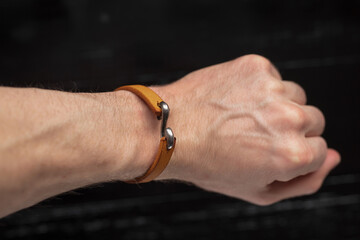 Brown leather bracelet on the male hand - obrazy, fototapety, plakaty