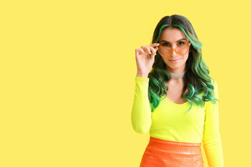 Beautiful young woman with unusual green hair on color background