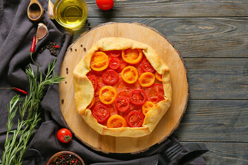 Board with tasty tomato galette and spices on wooden background