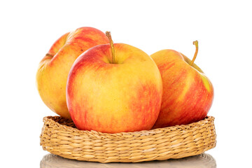 Three red juicy apples on a straw plate, macro, isolated on white.