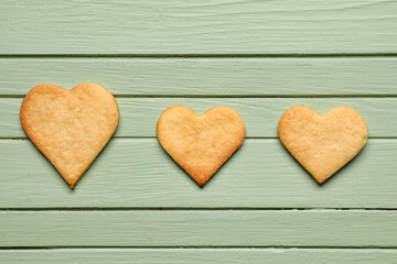 Tasty heart shaped cookies on green wooden background. Valentines Day celebration