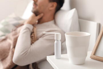 Obraz na płótnie Canvas Inhaler and cup of hot tea on table of ill man in bedroom
