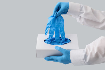 Doctor taking blue medical glove from box on light background